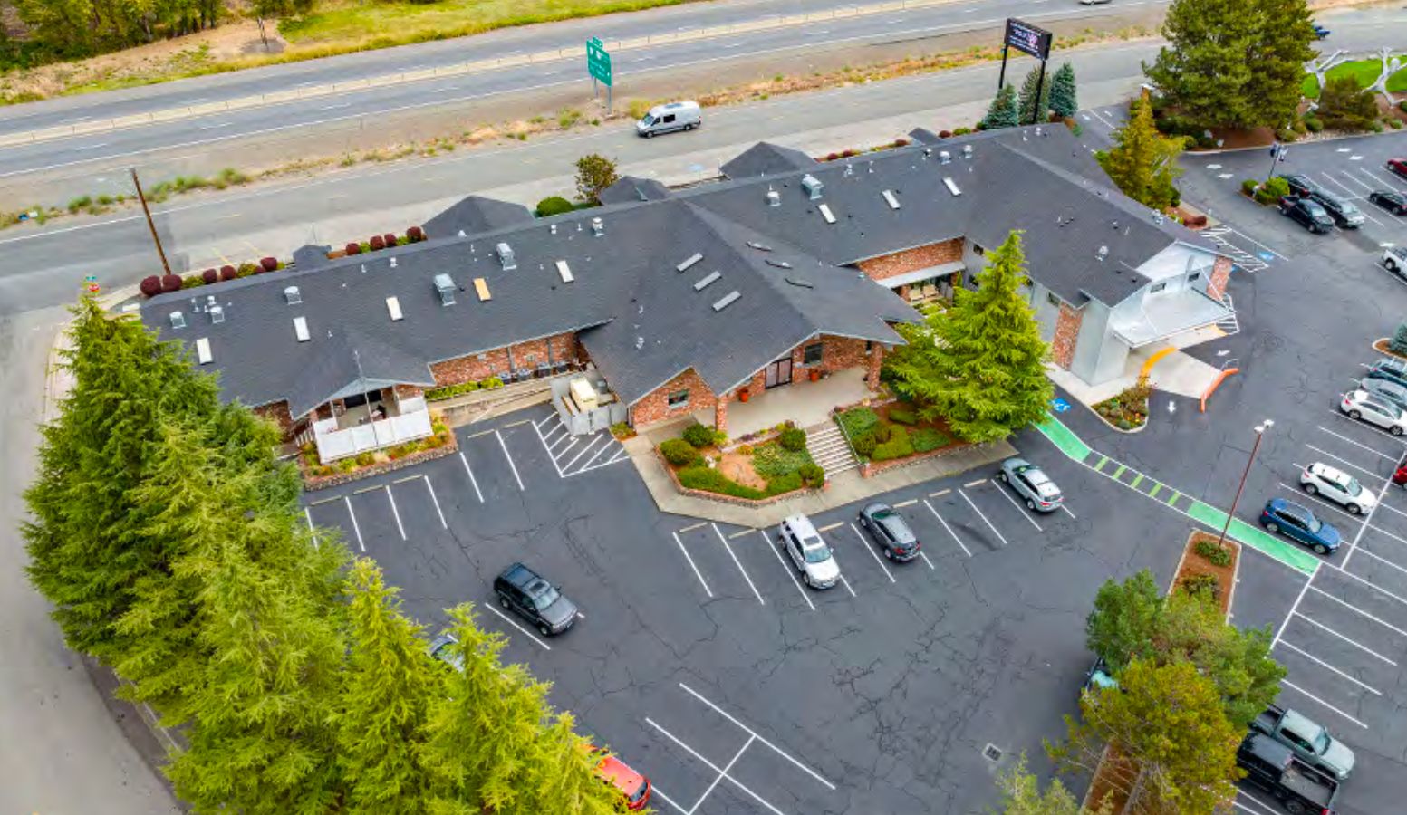 Aerial view of the 2166 NW Vine building with its parking lot and evergreen trees.
